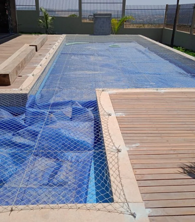 Piscina coberta com rede de proteção junto ao deck de madeira